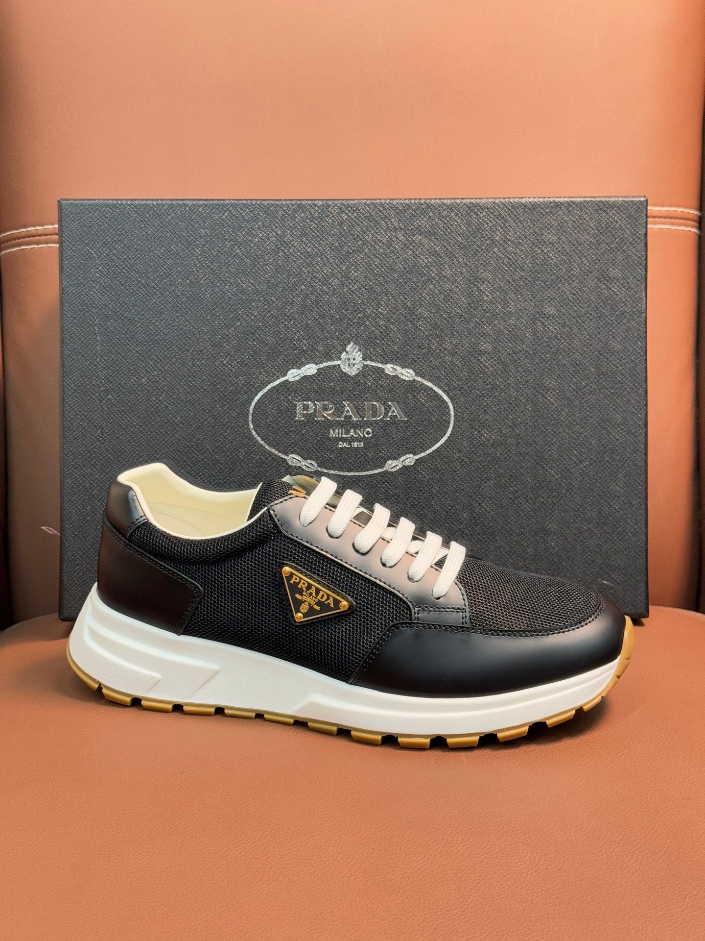 Prada unisex sneakers, dark upper, white laces, beige collar lining, yellow outsole.
