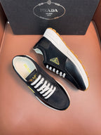 Prada unisex sneakers side view, dark upper, white laces, tan gum outsole.