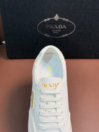 Prada unisex sneakers, white front view with lace row and gold logo on tongue