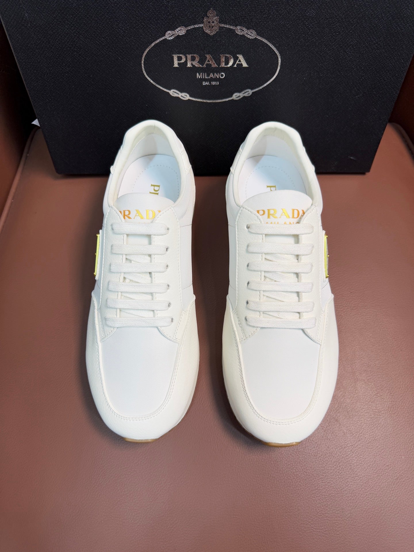 Prada unisex sneakers, white lace-up front with gold logo patch on tongue
