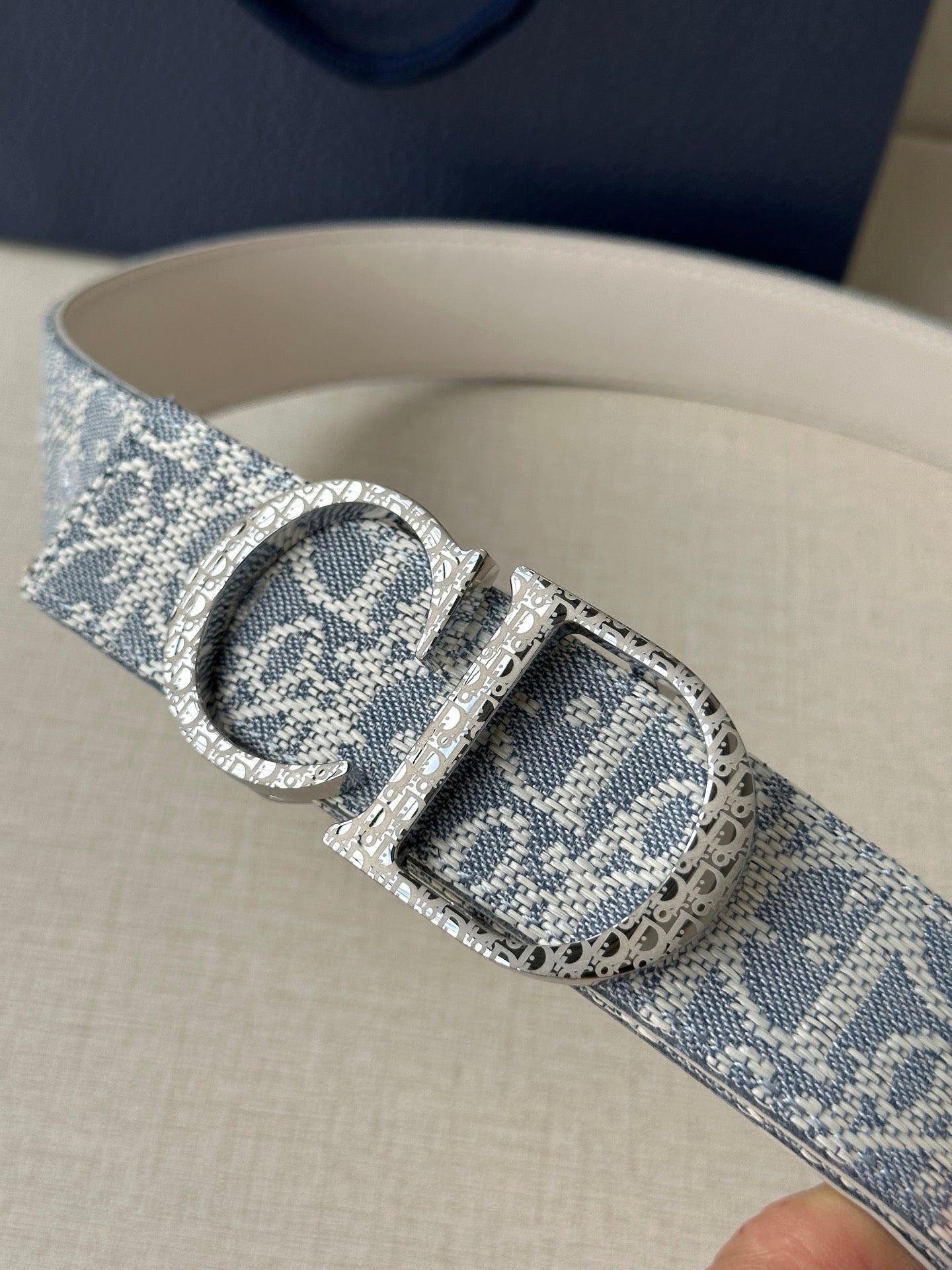 Dior logo belt close-up: blue patterned strap with engraved silver buckle