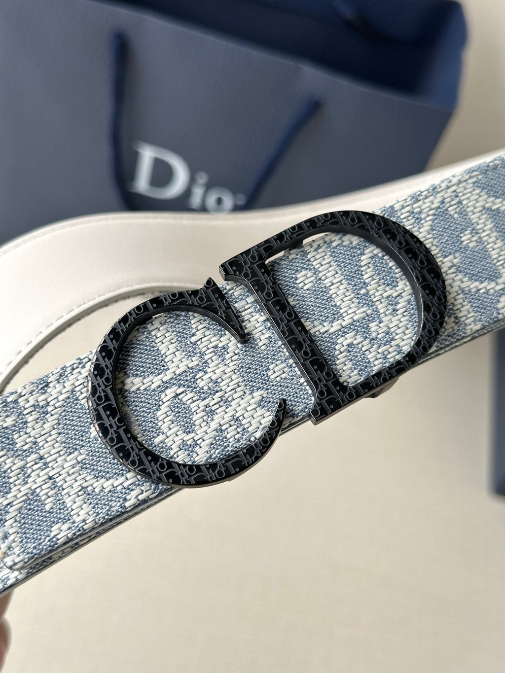 Dior logo belt buckle view: oval engraved silver detail on blue strap