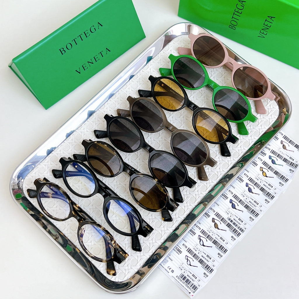 Assorted Bottega Veneta oval sunglasses with mixed frame colors and dark lenses in tray.