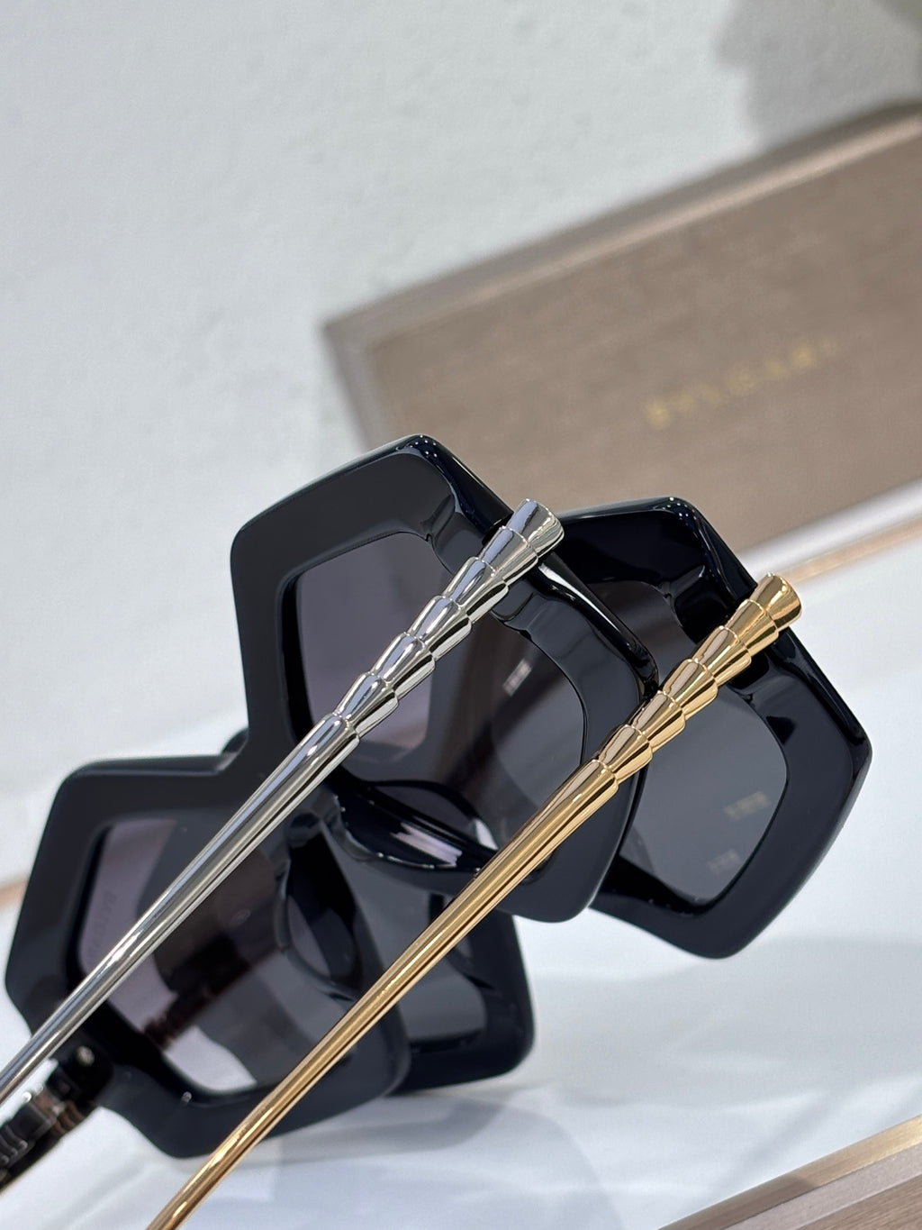 Sunglasses close-up, glossy black square frames with silver and gold temples