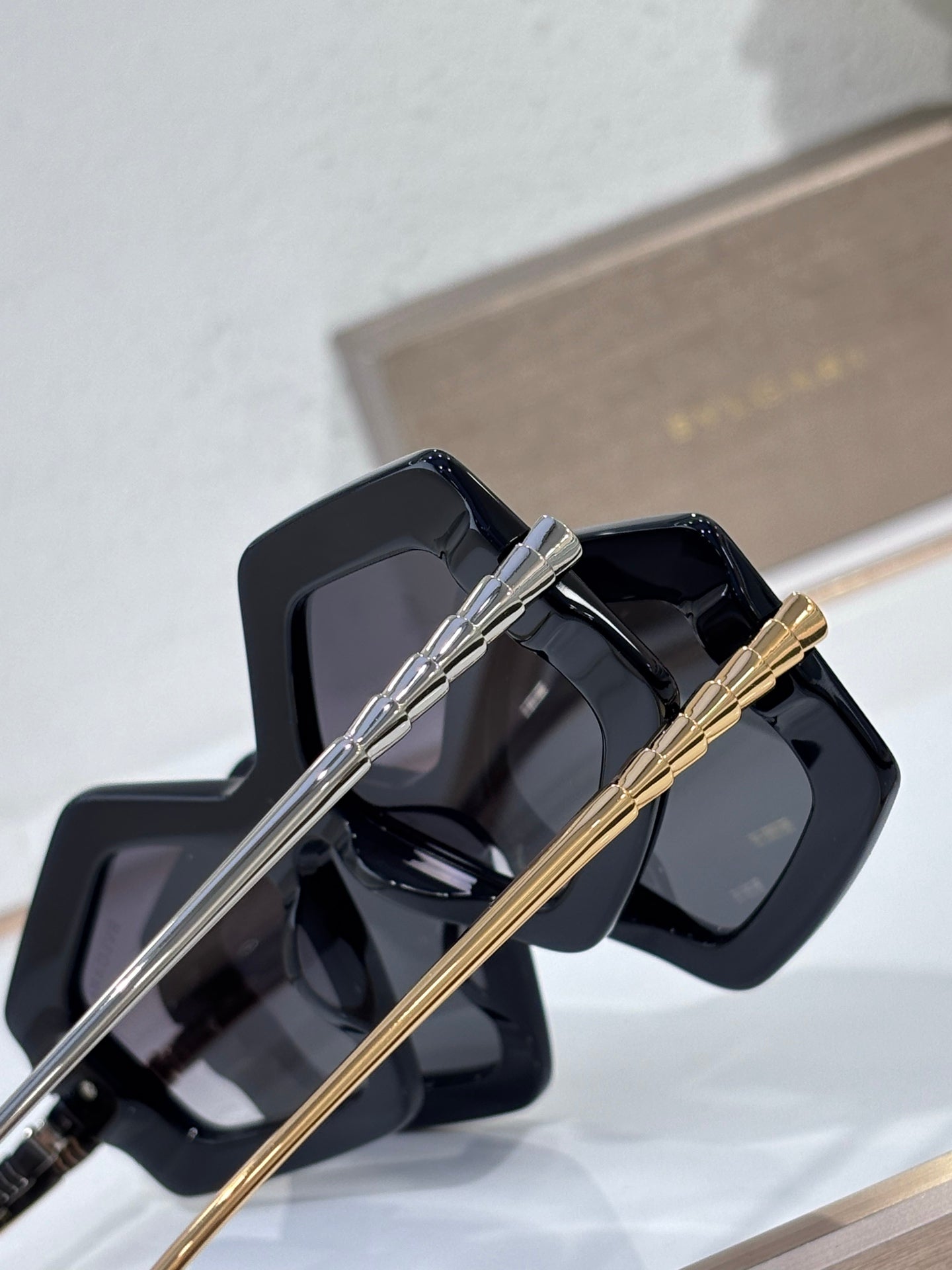 Sunglasses close-up, glossy black square frames with silver and gold temples