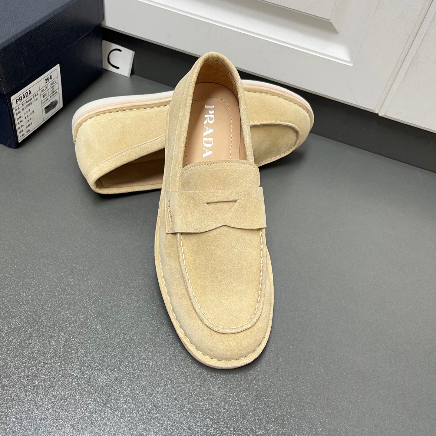 Beige Prada unisex loafers, top view showing PRADA logo on insole