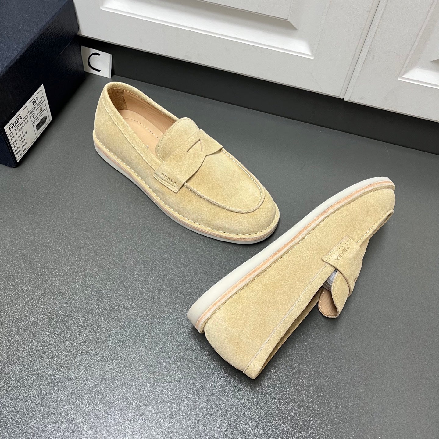 Beige Prada unisex loafers, one pair showing heel and side profile