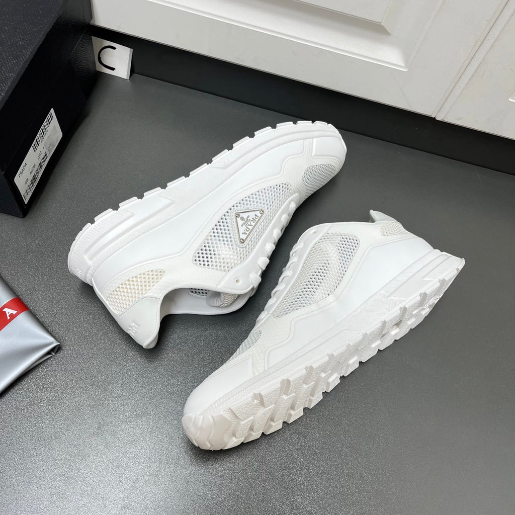 White Prada sneakers with side logo and thick treaded outsole, angled view