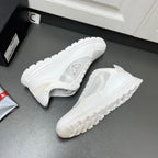 White Prada sneakers with side logo and thick treaded outsole, angled view