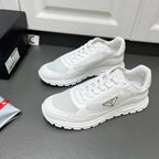White Prada sneakers showing lace-up mesh upper and textured side logo patch