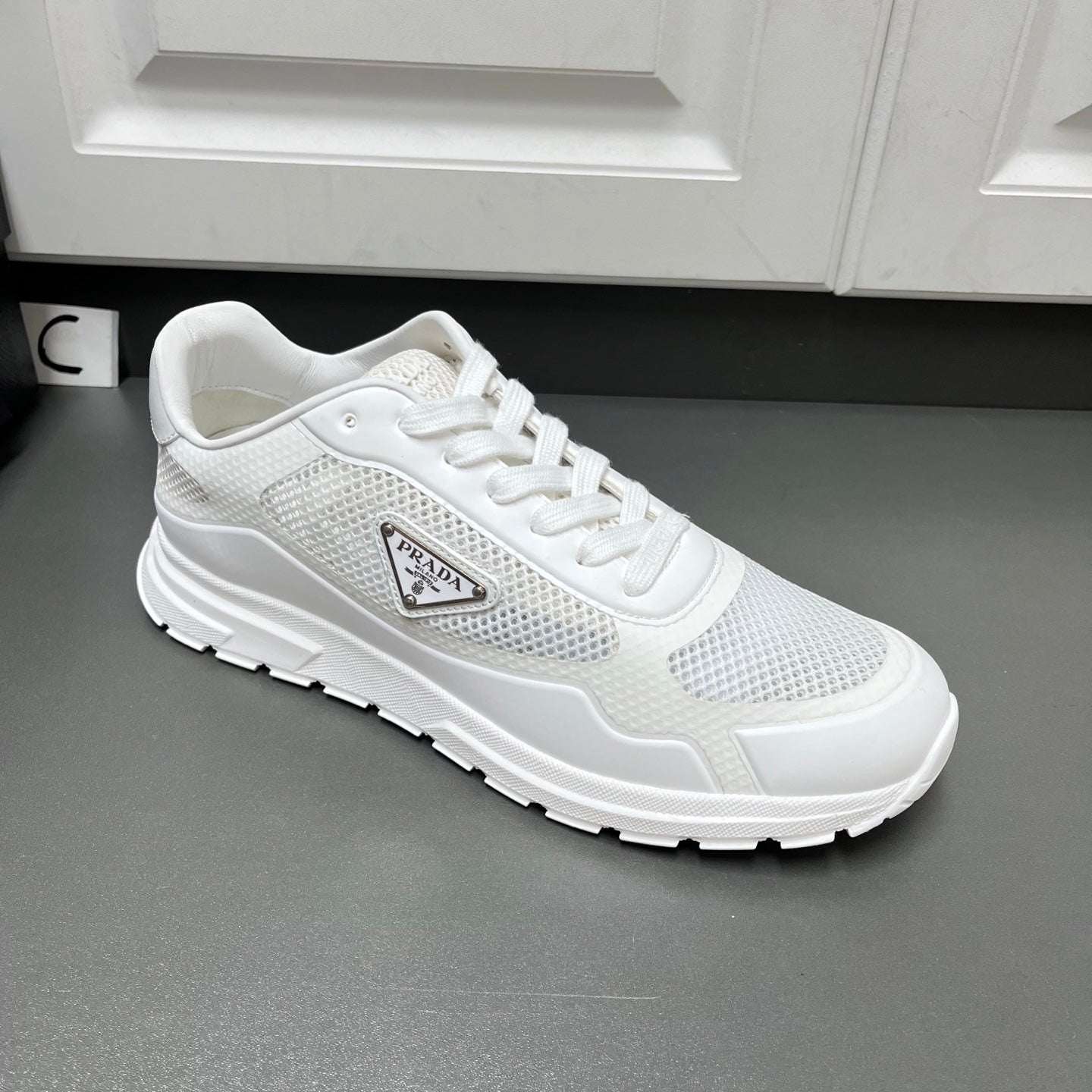 White Prada sneakers with lace-up front, mesh paneling, and chunky sole