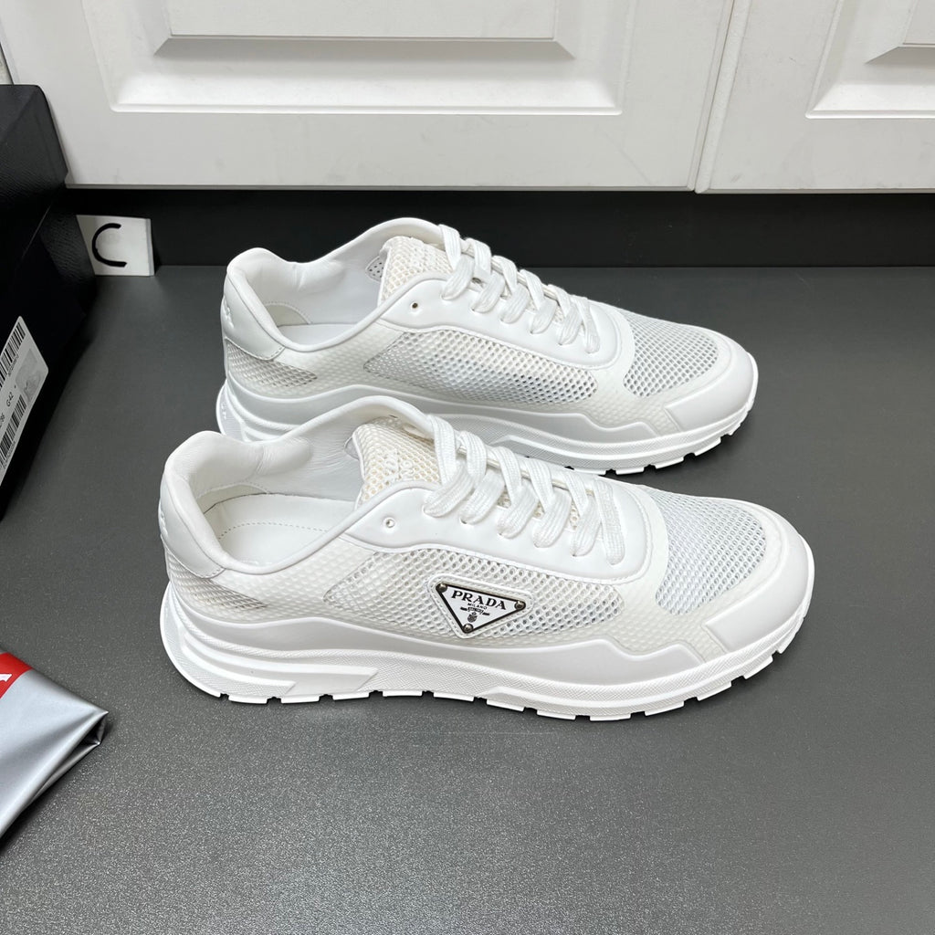 Pair of white Prada sneakers with lace-up mesh uppers and sculpted tread sole