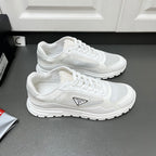 Pair of white Prada sneakers with lace-up mesh uppers and sculpted tread sole