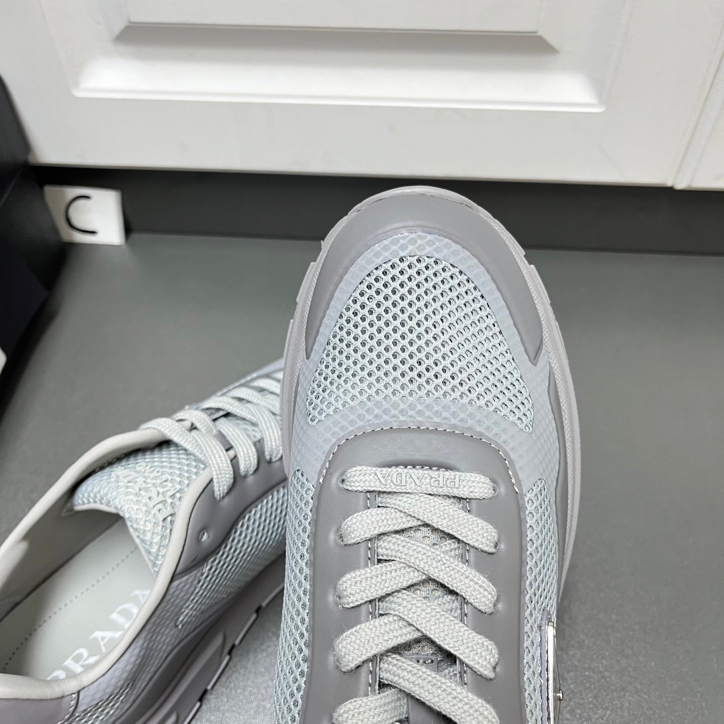 Prada unisex sneakers close-up of toe and lace-up, light gray mesh texture