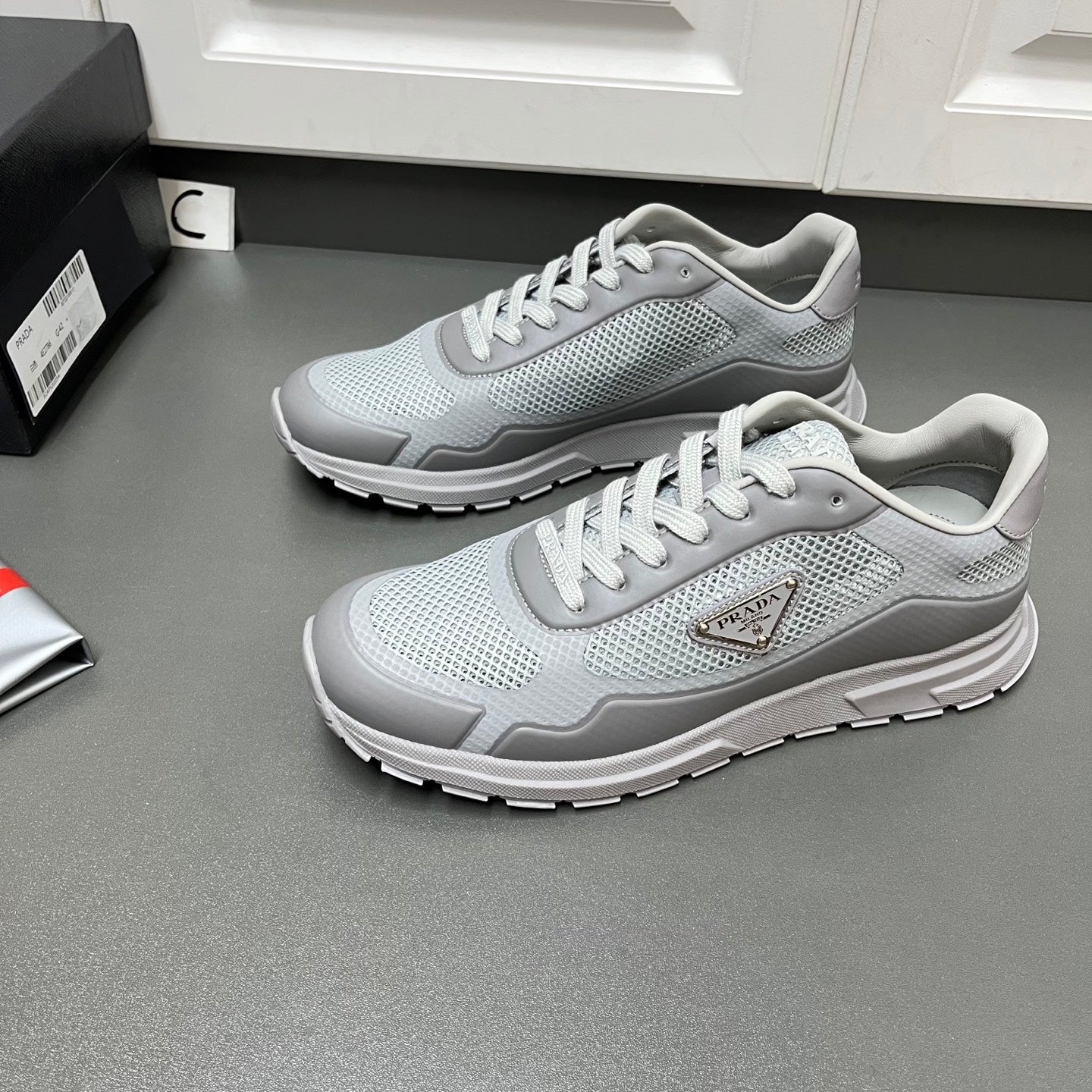 Prada unisex sneakers, light gray mesh style with lace-up front and logo patch