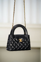 Black Chanel quilted mini handbag with top handle and gold chain shoulder strap