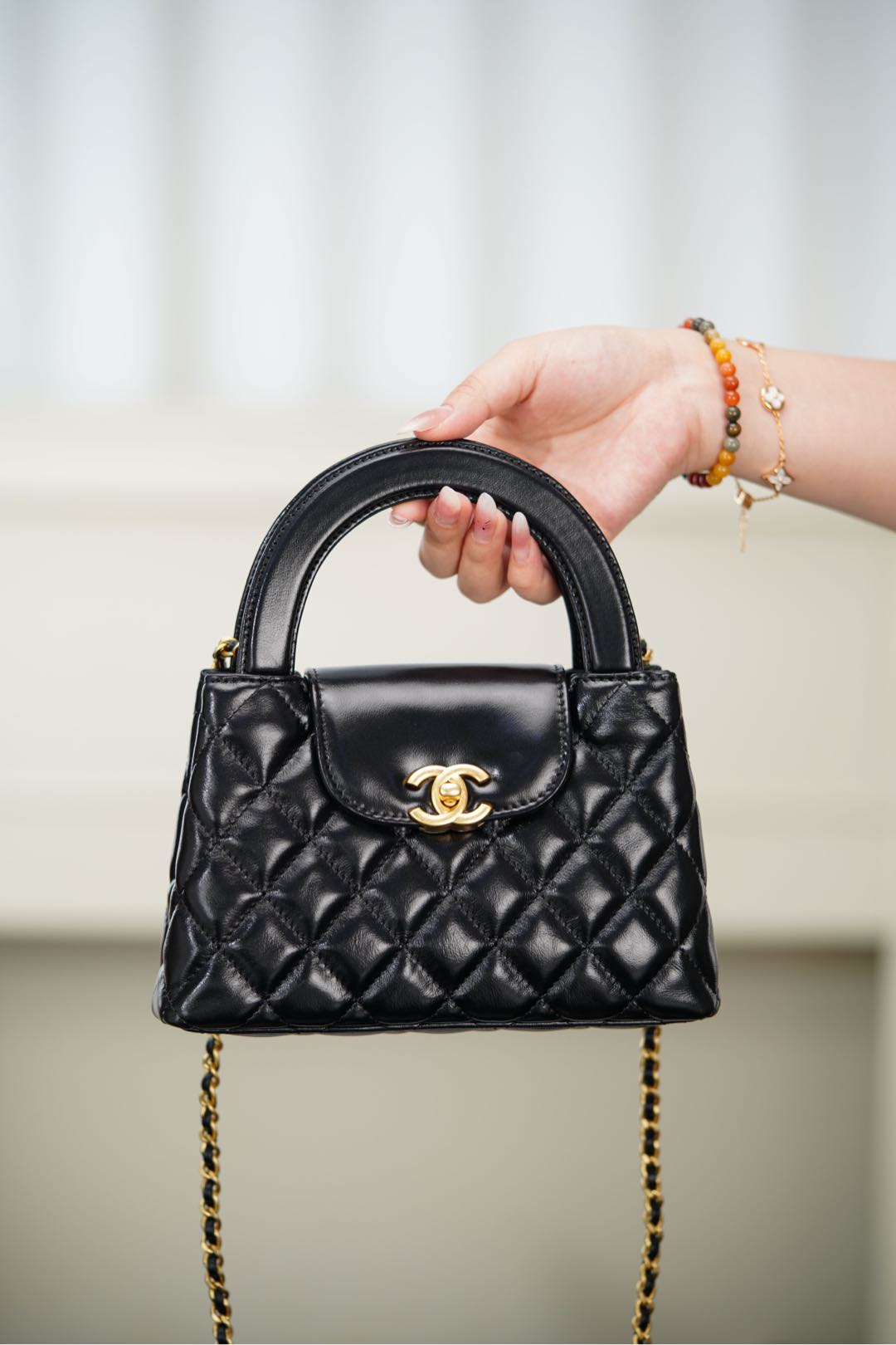 Black Chanel quilted mini handbag with curved top handle and CC clasp