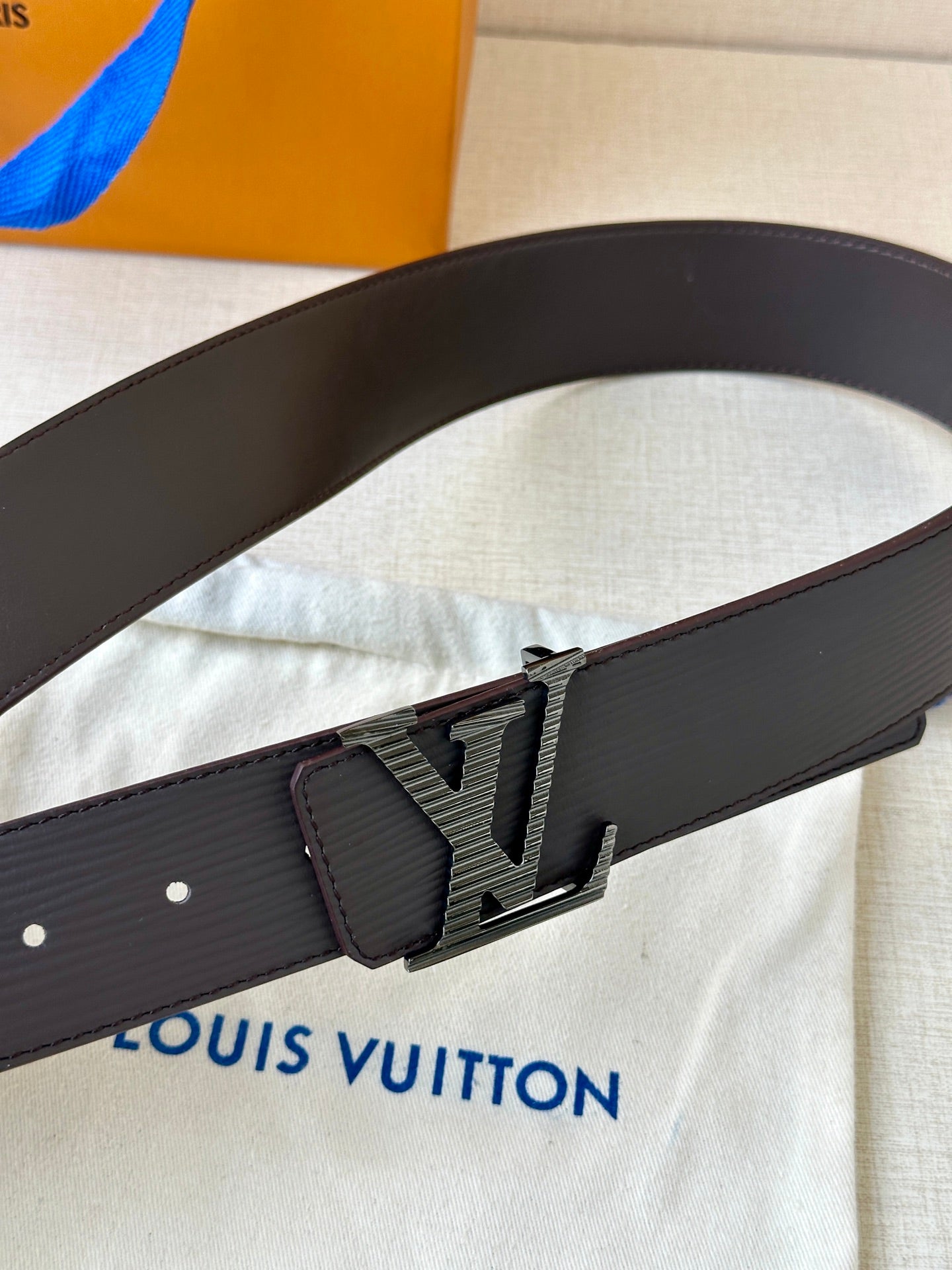 Louis Vuitton belt with dark strap and oversized LV logo buckle, close-up.