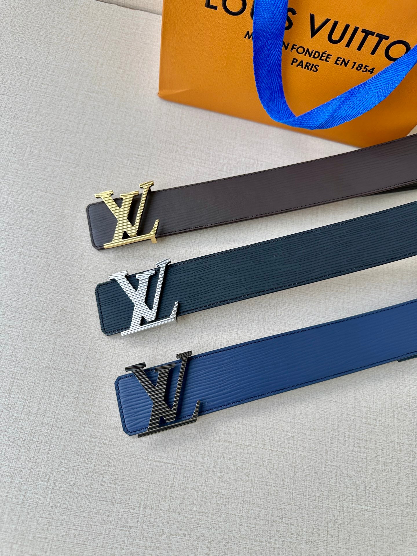 Louis Vuitton belt with LV buckles in black and blue tones, laid flat.
