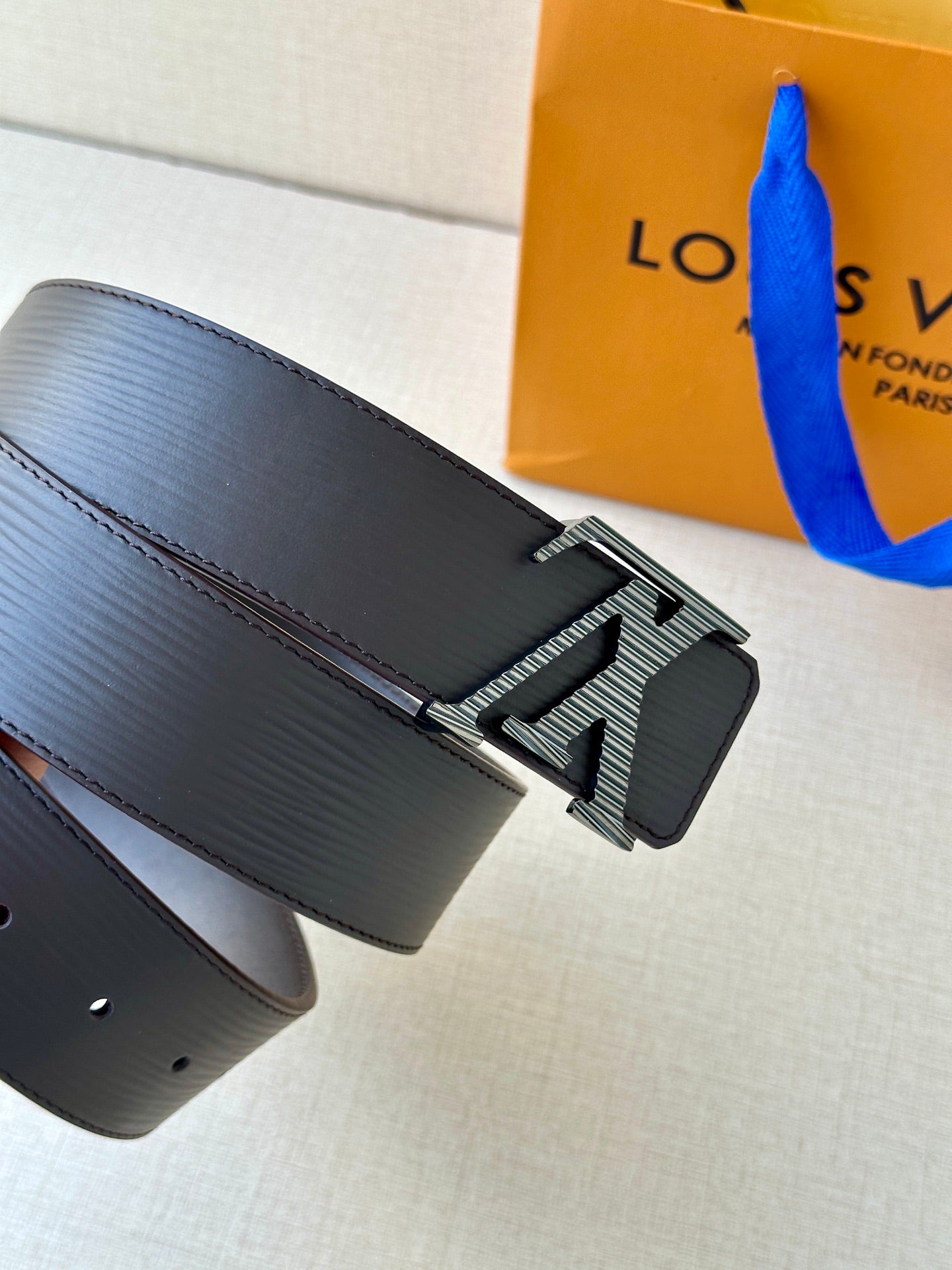 Louis Vuitton belt with dark textured leather strap and LV buckle detail.