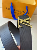 Louis Vuitton belt with textured dark strap and gold LV buckle, close-up.