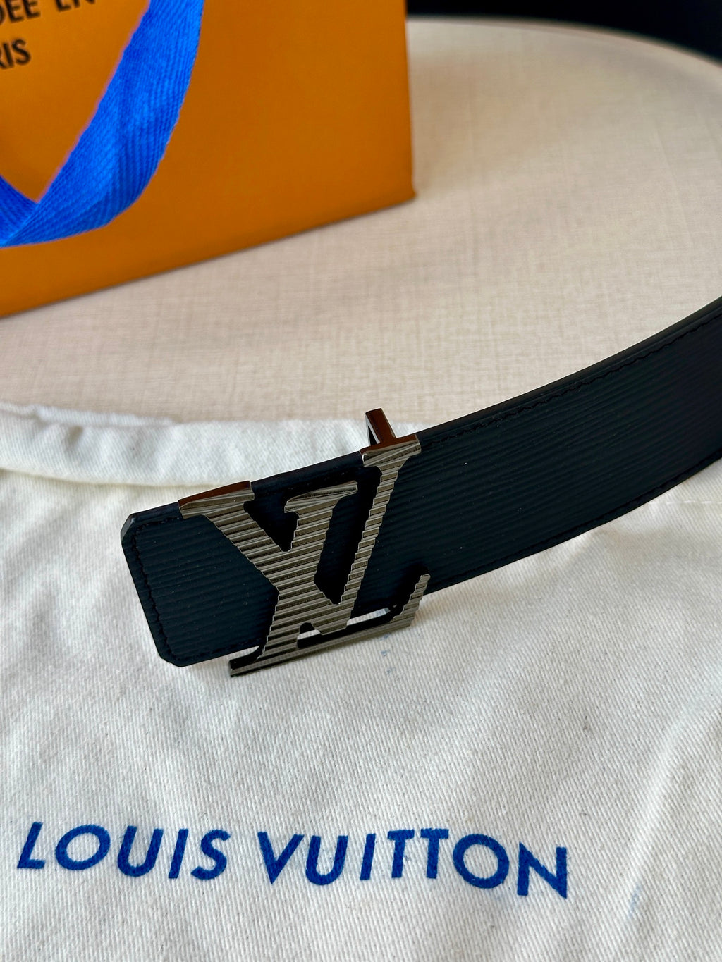 Louis Vuitton belt buckle detail with LV monogram on dark blue strap