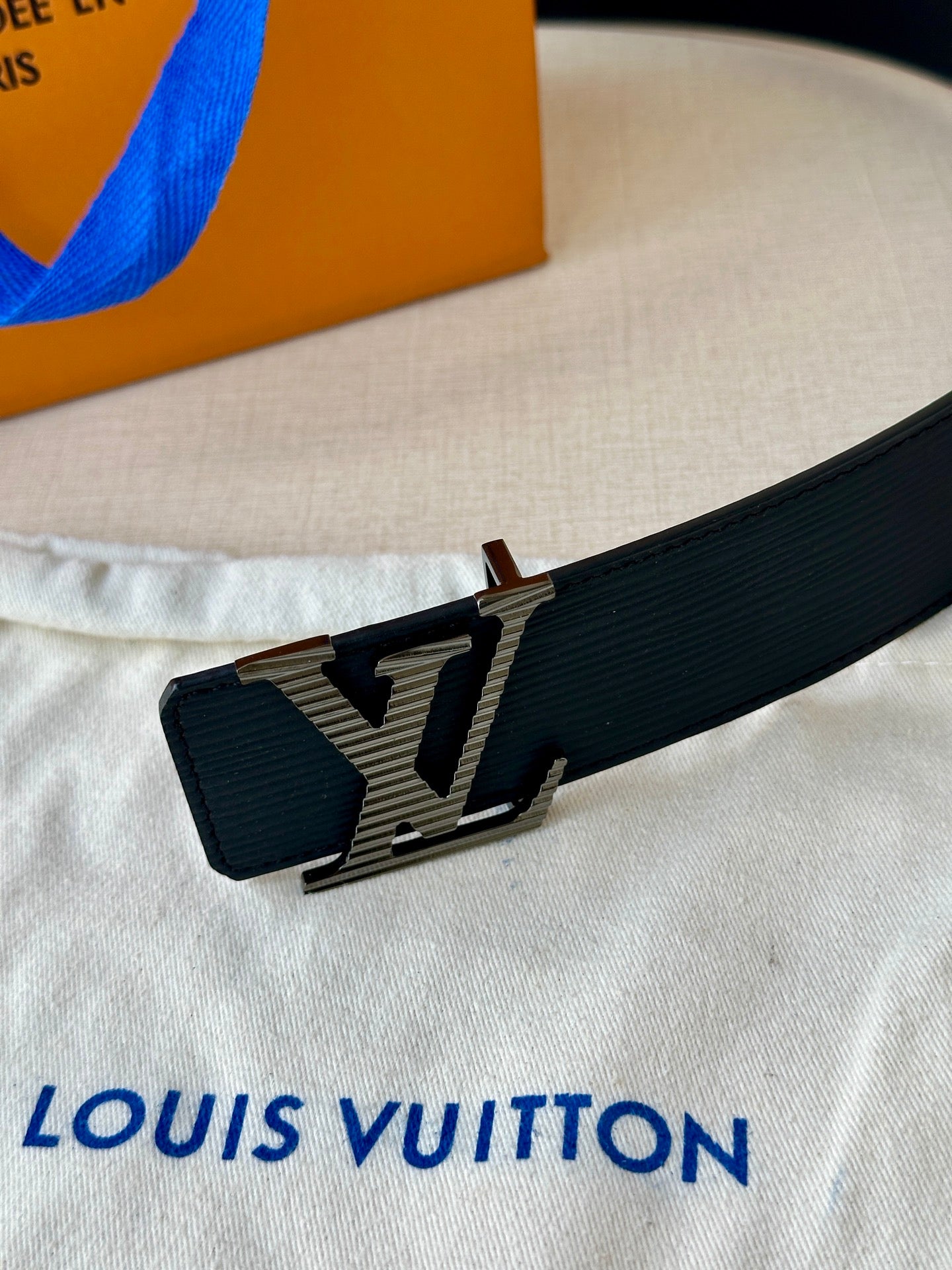Louis Vuitton belt buckle detail with LV monogram on dark blue strap