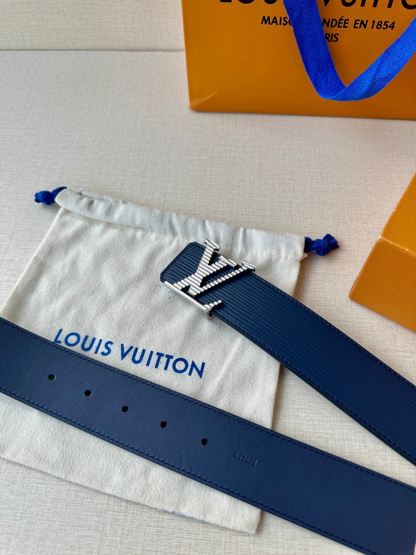 Blue leather belt with gold-tone LV buckle and visible adjustment holes