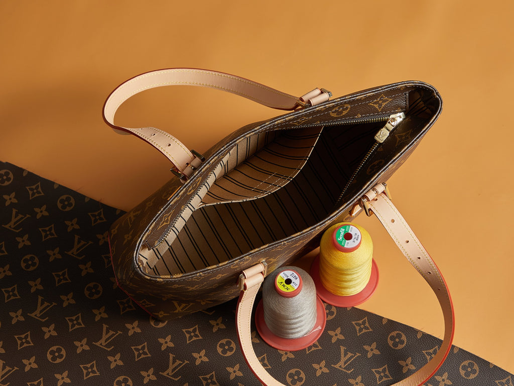 Louis Vuitton monogram bag open to striped interior with strap and gold hardware.