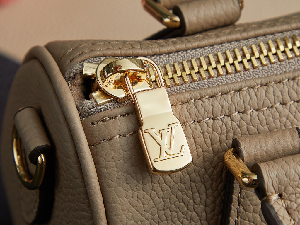 Louis Vuitton monogram handbag zipper close-up with gold pull and LV charm on beige leather