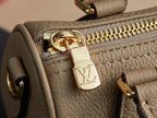 Louis Vuitton monogram handbag zipper close-up with gold pull and LV charm on beige leather