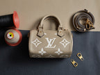 Louis Vuitton monogram handbag in beige with two top handles, gold hardware, and shoulder strap