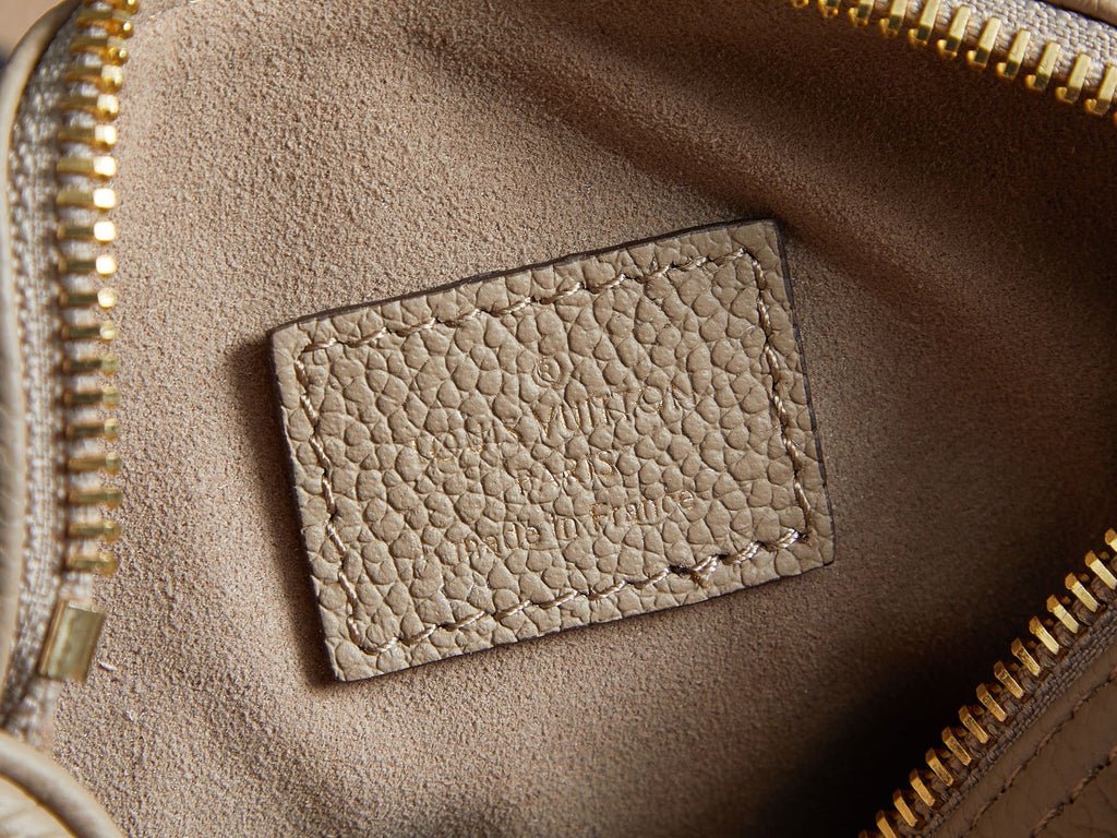 Louis Vuitton monogram handbag interior close-up: beige pocket panel with gold zipper teeth