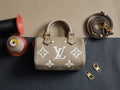 Louis Vuitton monogram handbag in beige with top handles, gold hardware, and strap rings
