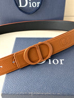 Tan leather belt with oval CD buckle and embossed logo pattern on strap