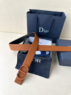 Tan leather belt with CD buckle and embossed lettering detail on strap