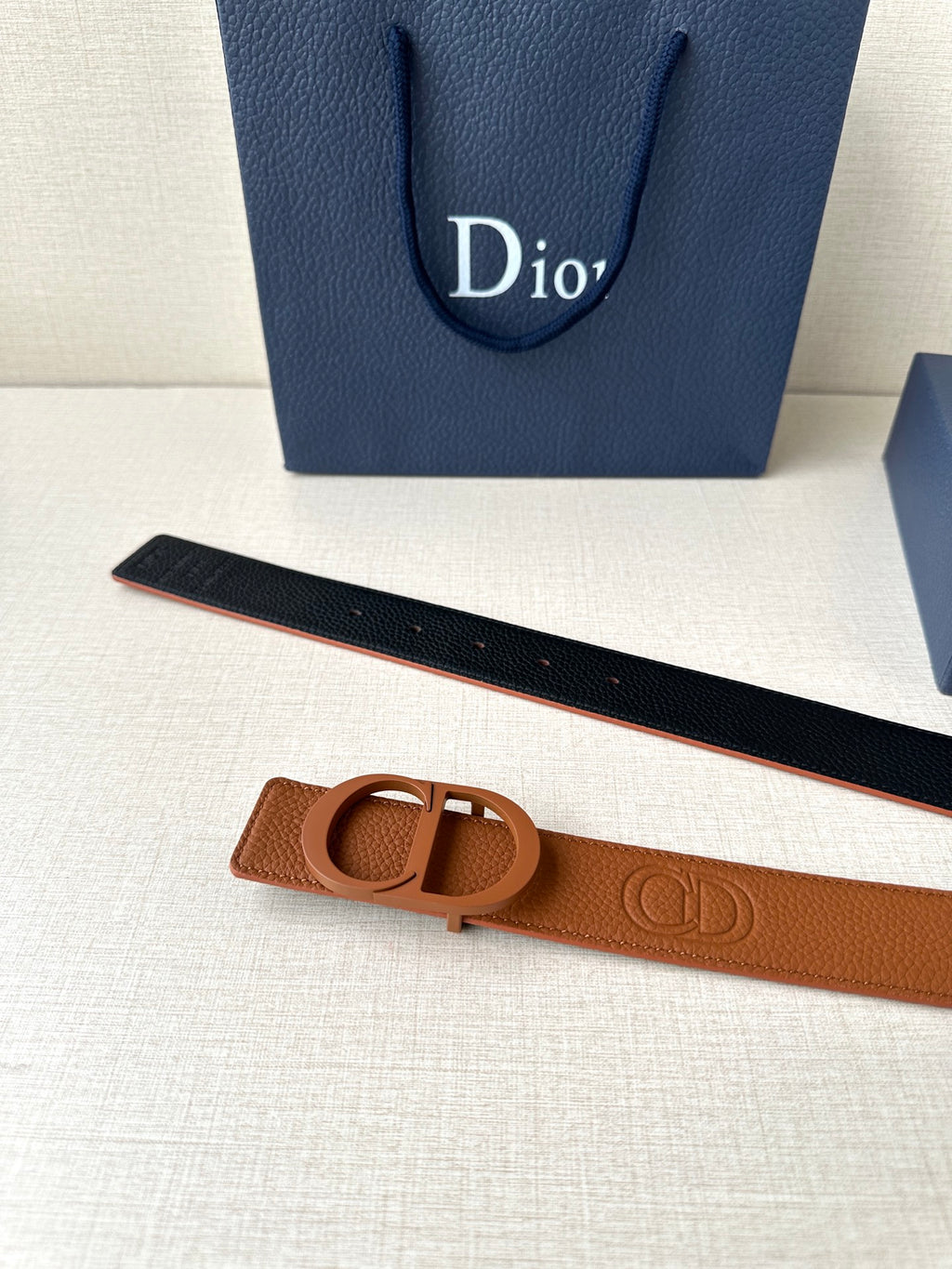 Tan leather belt with CD buckle and dark underside visible