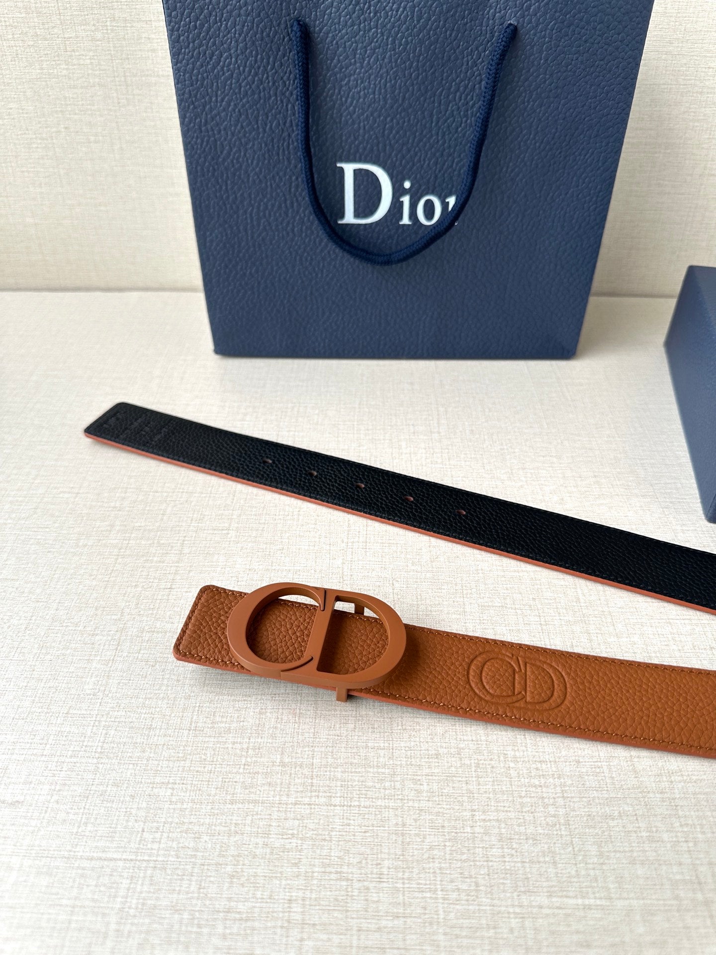 Tan leather belt with CD buckle and dark underside visible