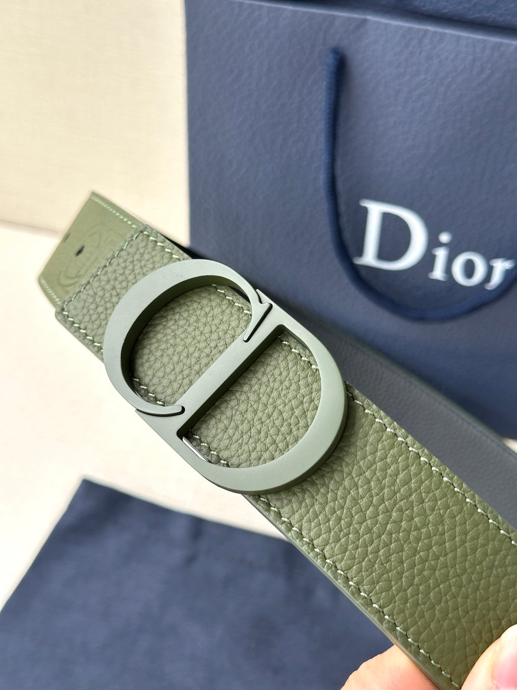 Dior belt buckle close-up on olive green leather with circular metal clasp
