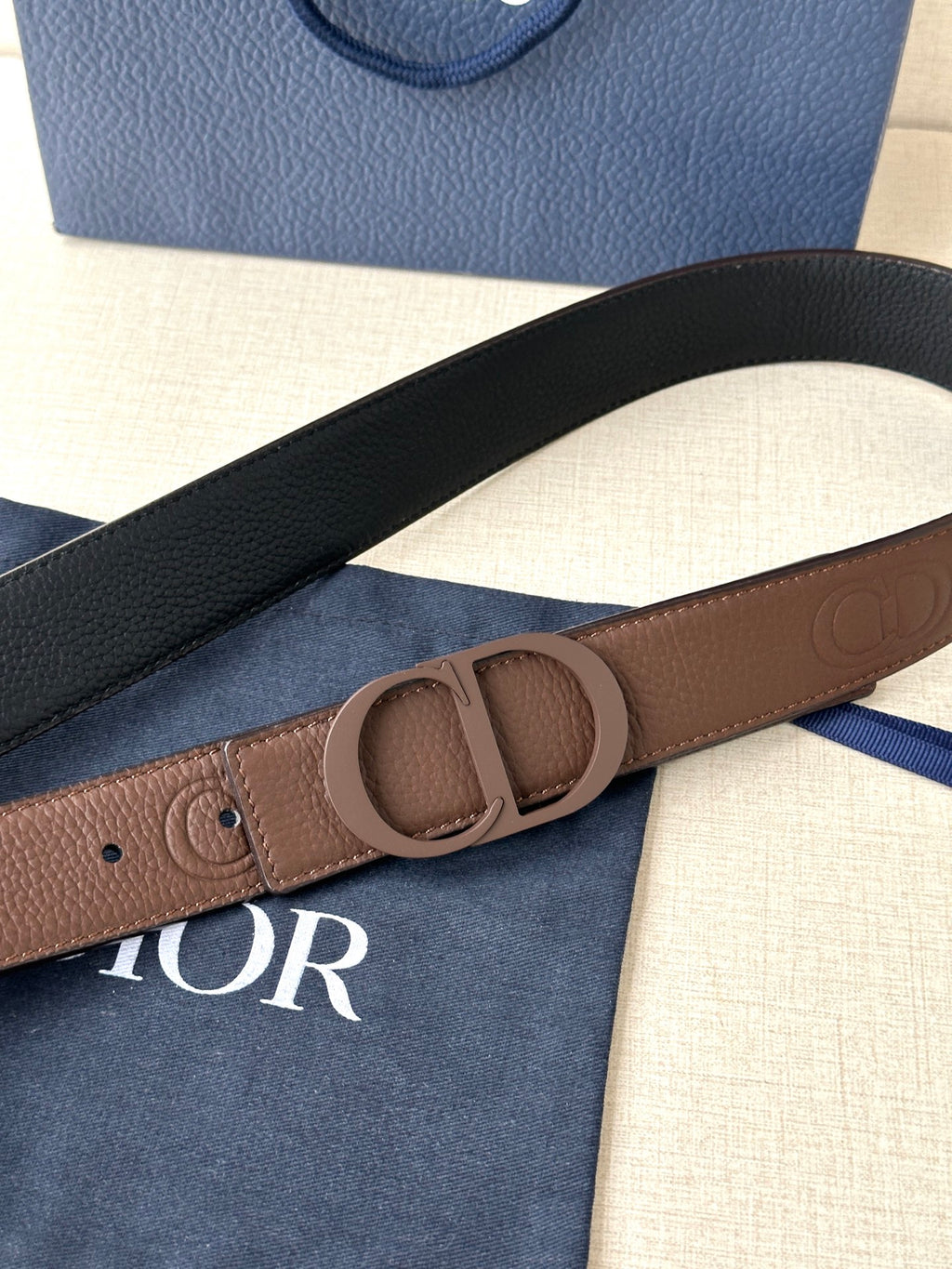 Dior leather belt close-up: brown strap with embossed buckle and hole rows