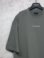 Balenciaga short-sleeve T-shirt on hanger, dark gray-green with small chest logo.