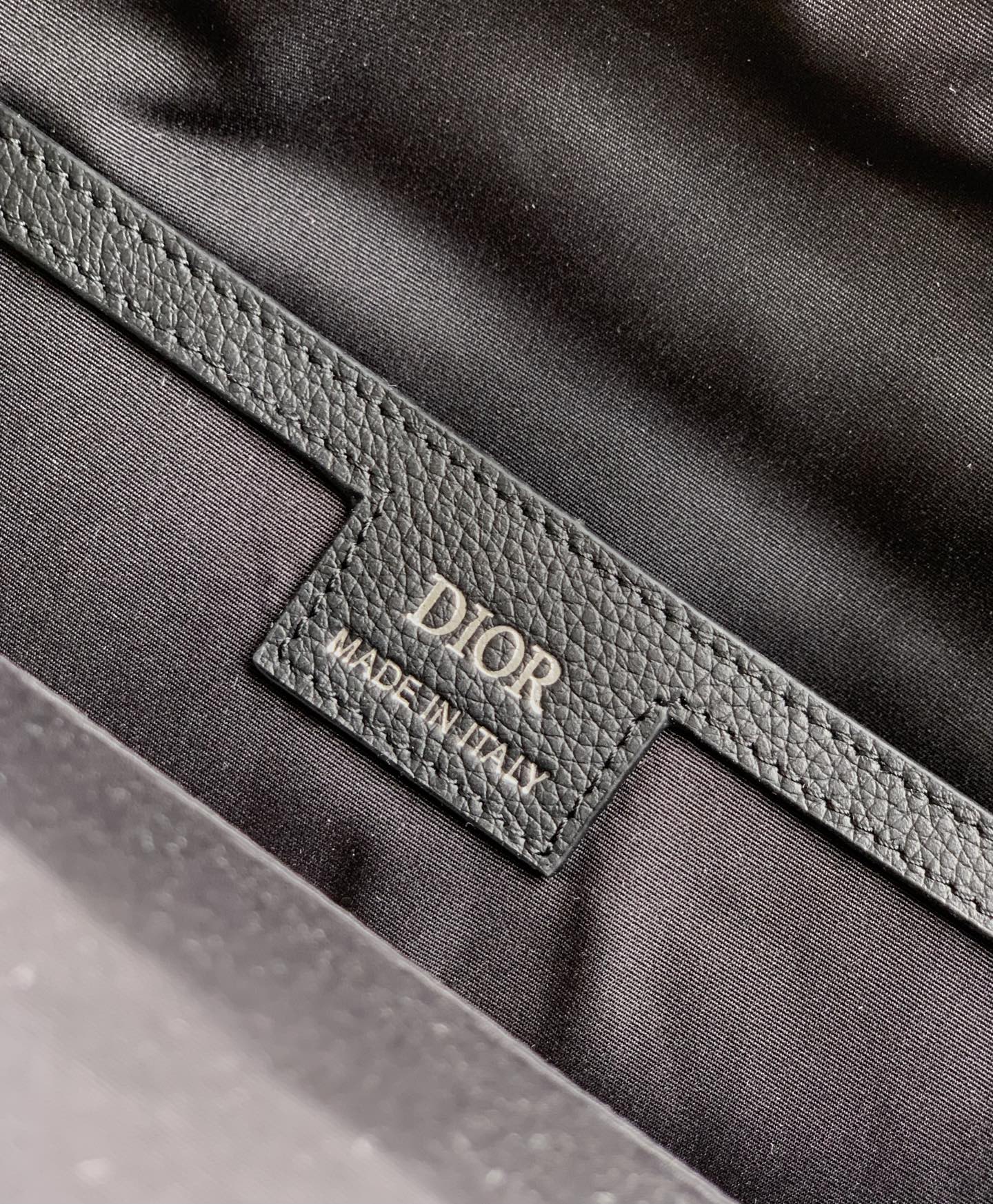 Leather brand tag on backpack lining reading Dior and Made in Italy