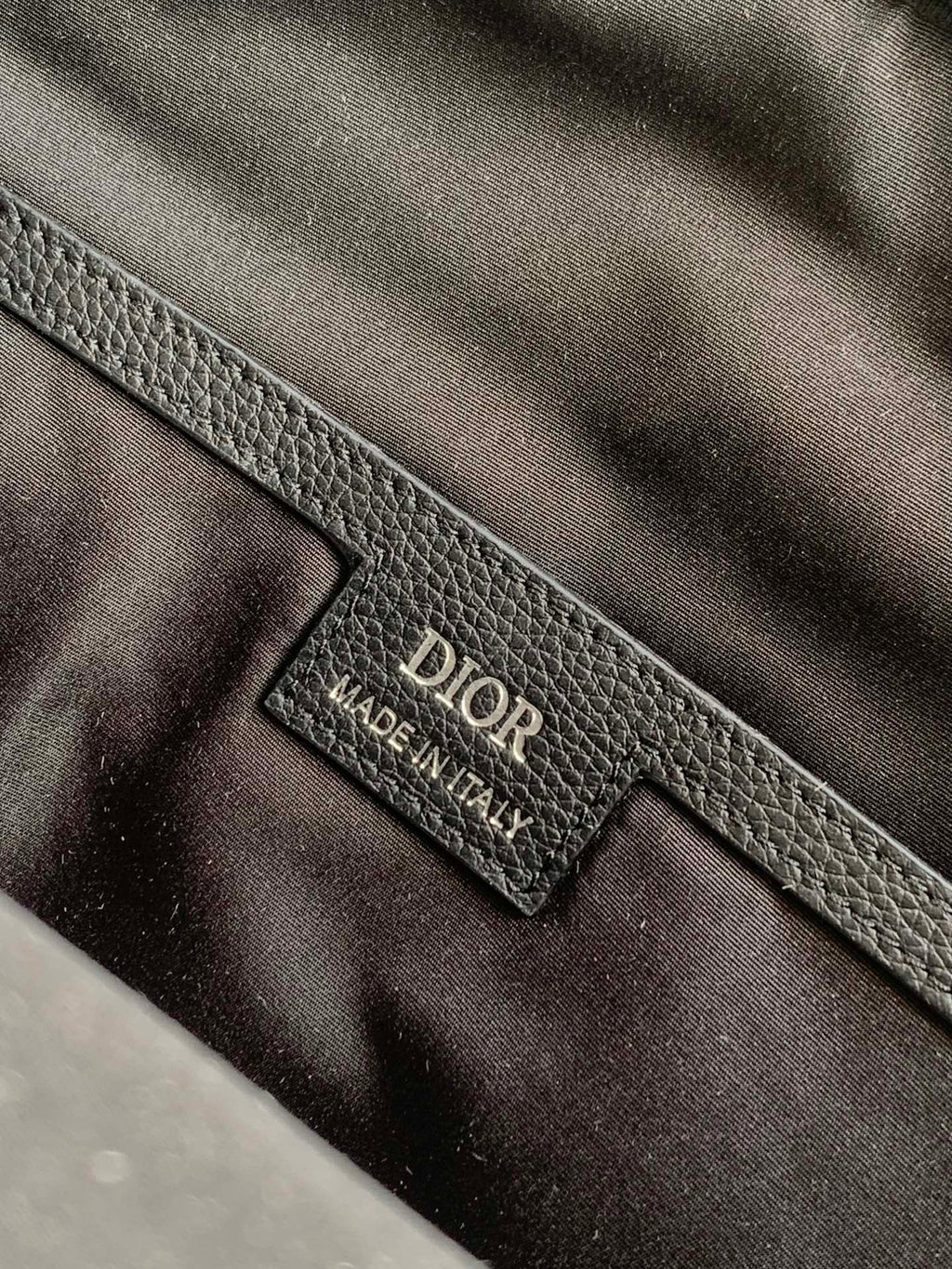 Dior logo leather interior label on gray-black bag lining, close-up