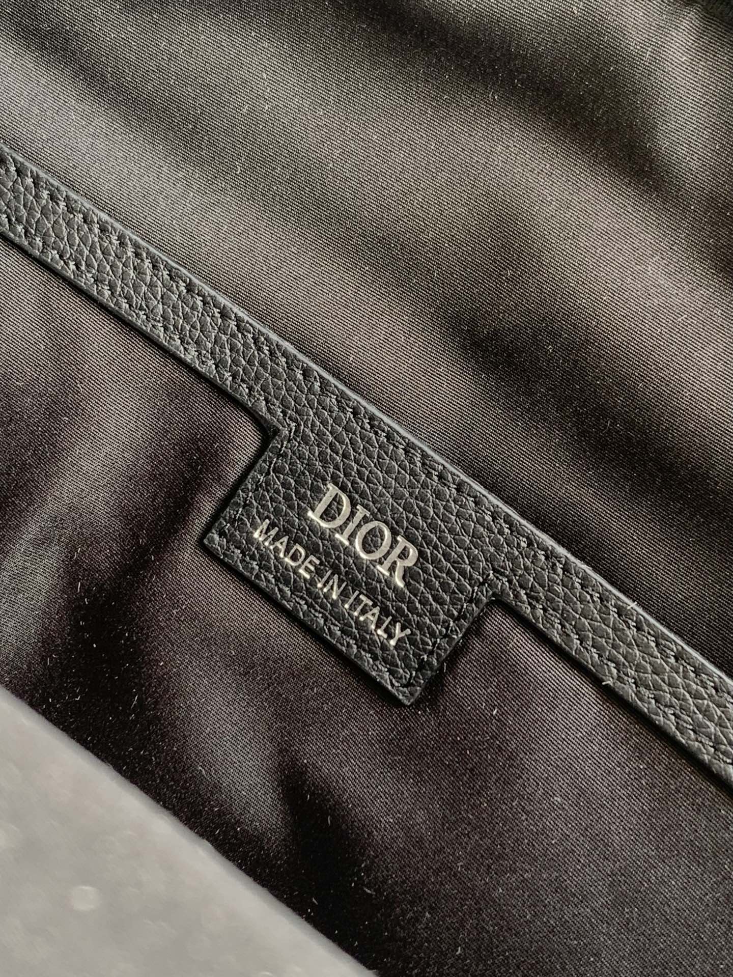Dior logo leather interior label on gray-black bag lining, close-up