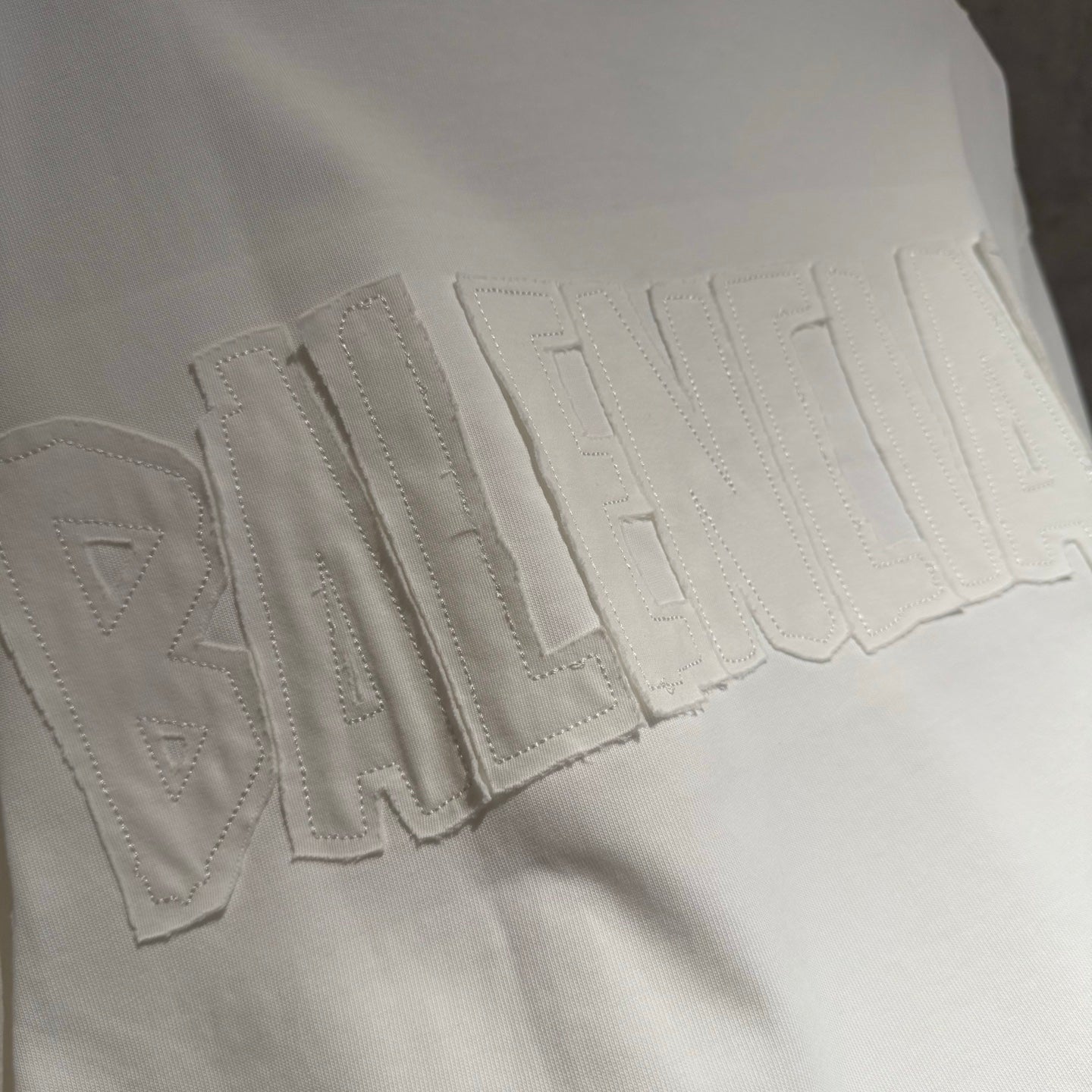White Balenciaga T-shirt close-up of raised BALENCIAGA lettering on fabric