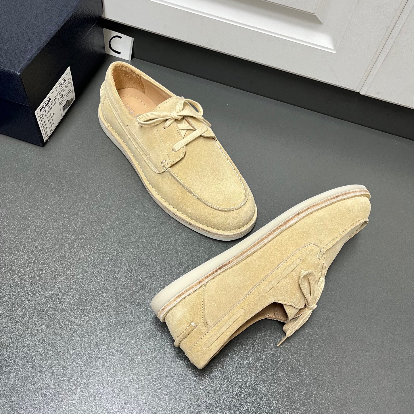 Beige suede lace-up loafers with folded heel detail and flat white rubber sole