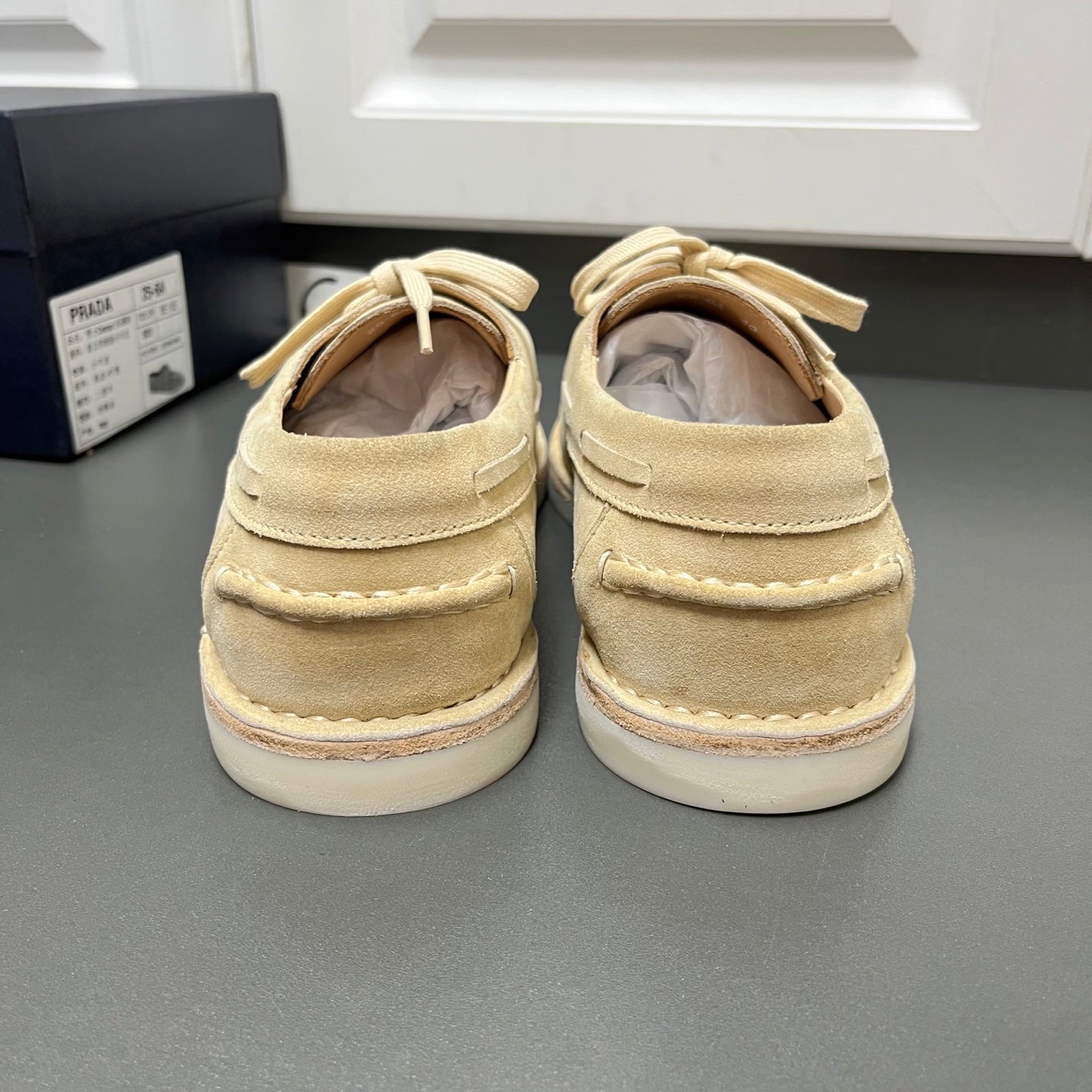 Beige suede lace-up shoes from the back with white midsoles and looped laces