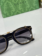 Round sunglasses close-up with dark lens and gold-trim black frame