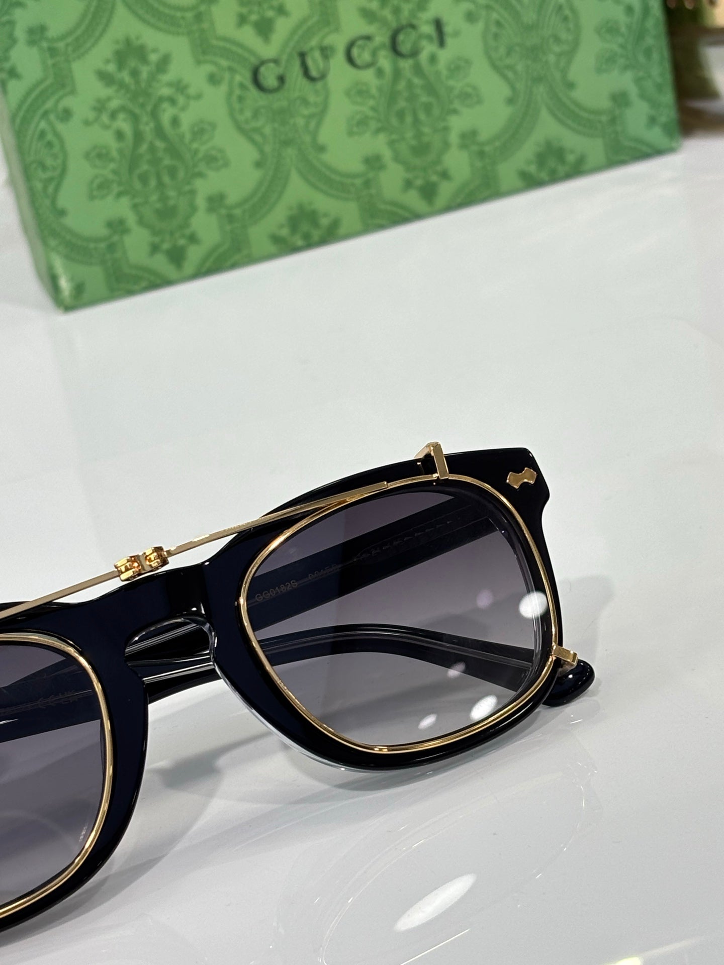 Round sunglasses close-up with dark lens and gold-trim black frame
