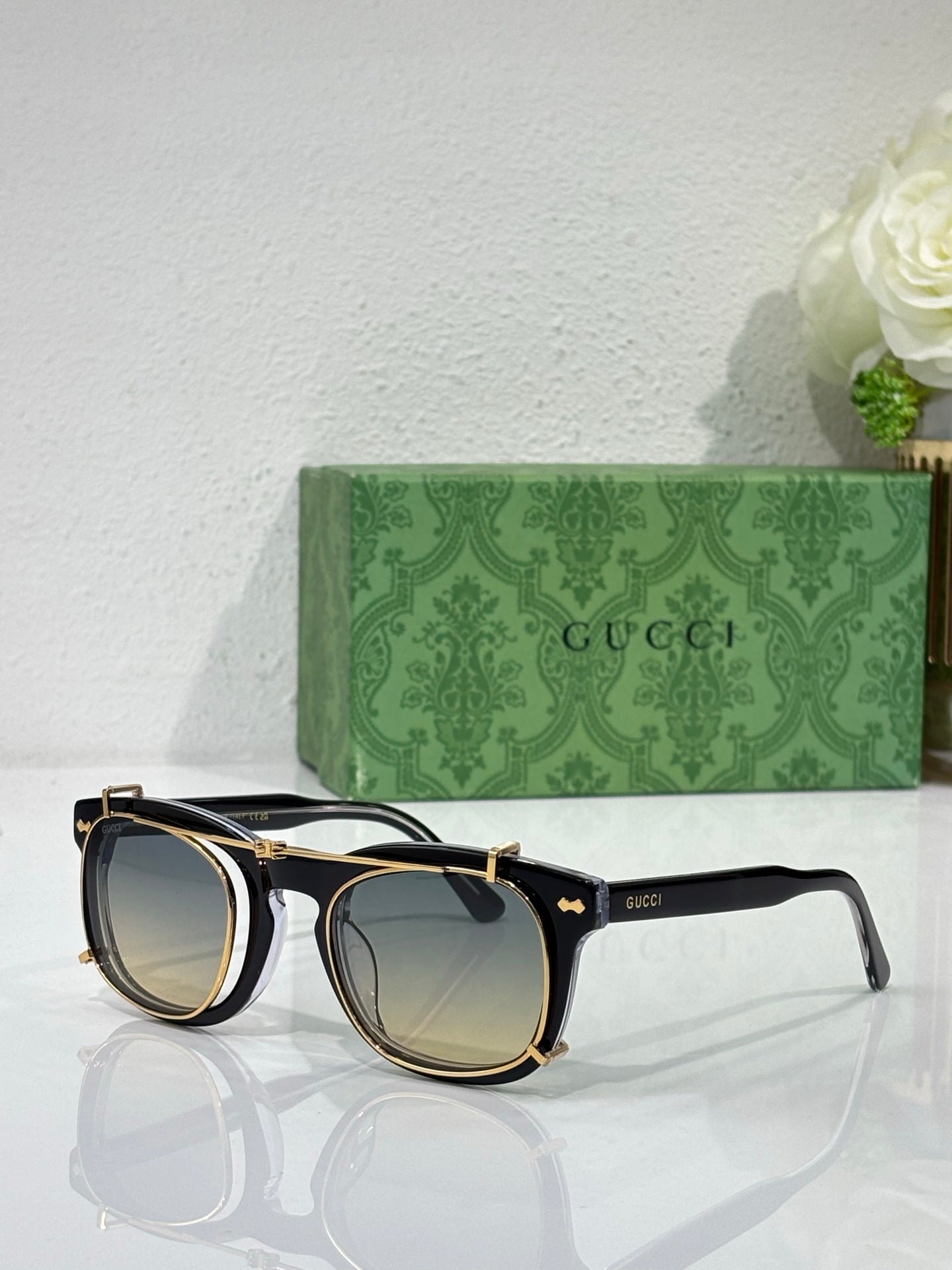 Round sunglasses with black and gold frames, dark lenses